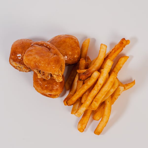 Three glazed chicken sliders and a pile of golden french fries.