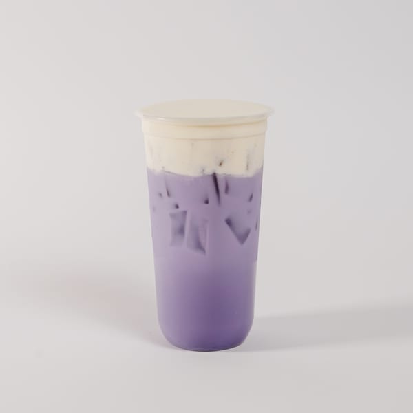 Purple iced drink with white cream foam topping in a clear plastic cup.